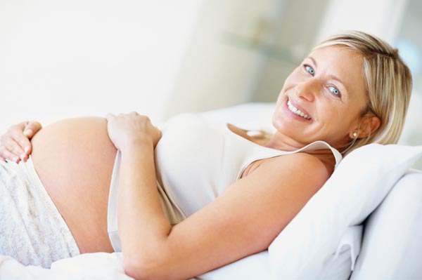 Portrait of a beautiful middle aged pregnant female smiling on the couch